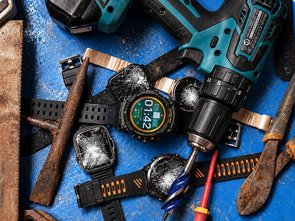 Four black smartwatches with shattered glass screens are arranged on a blue workbench alongside a teal cordless drill, rusty tools, and a screwdriver.